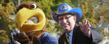 <p>Flash, Kent State's mascot, waves to spectators along the Homecoming parade route along with Kent State President Lester A. Lefton.</p>