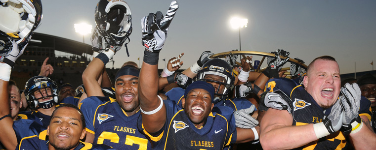 Kent State football players celebrate with the Wagon Wheel trophy following a 28-17 victory over the visiting Akron Zips.