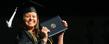 <p>An undergraduate student displays her diploma, and a proud grin, following commencement ceremonies.</p>