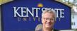 Mark Mothersbaugh, a founding member of the band Devo and music composer for television and movies, poses near the Kent State sign outside of Franklin Hall.