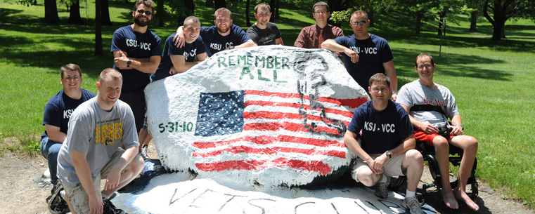 Members of the Kent State University Veteran's Campus Club pose around the rock on front campus.