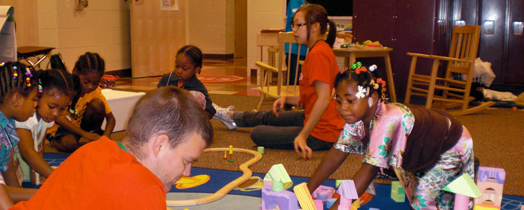 A Kent State student assists kindergarten children with an art project. The Bridges to Kindergarten program is a collaboration between the agency Project GRAD Akron and early childhood faculty and students at Kent State. (Photo courtesy of Janice Kroeger, Kent State University.)<br />