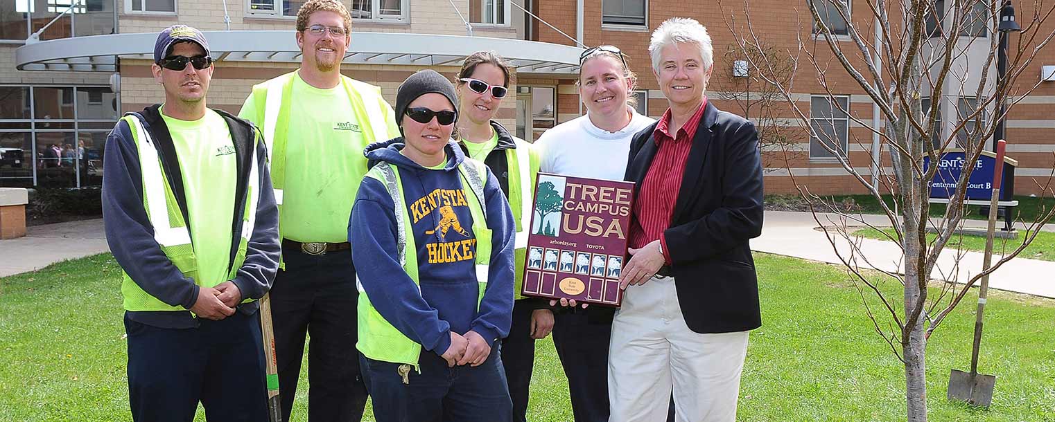 Heather White (right), grounds manager of University Facilities Management at Kent State, displays Kent State’s Tree Campus USA designation following the 2014 Arbor Day tree planting ceremony in the courtyard of Centennial A and B. She is pictured with grounds employees who helped the university earn this designation for a sixth consecutive year.