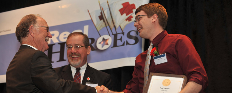 Eric Johnston, a senior Kent State University student majoring in music, accepts an award from Glenn Saltzman, Ph.D., during the American Red Cross of Summit and Portage Counties’ 2012 Real Heroes Breakfast event. Johnston rescued a girl from drowning in the Cuyahoga River in Kent.