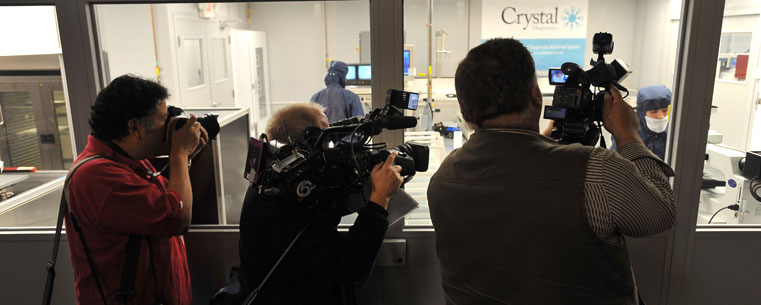 Photographers and videographers film workers making MultiPath System cassettes in the clean room at Crystal Diagnostics.