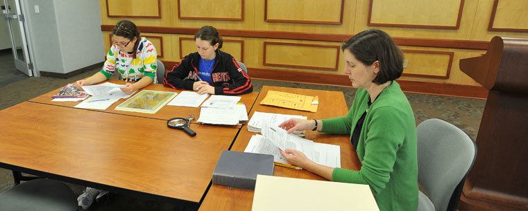 Dr. Jennifer Larson, chair of Kent State's Department of Modern and Classical Language Studies, works with undergraduate studentsOla Sobieska and Heather Benya as they study an ancient Greek papyrus document.