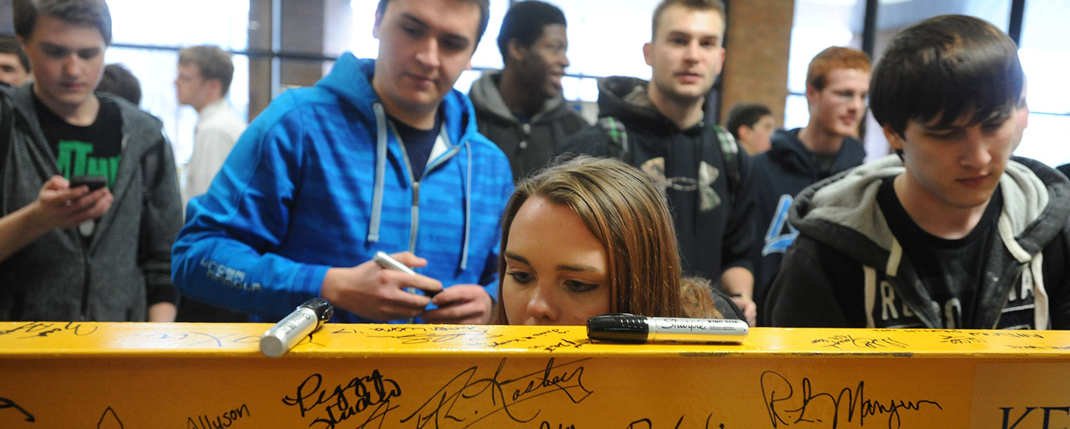 Kent State students take turns signing the I-beam that will be installed in the new building for the College of Applied Engineering, Sustainability and Technology.