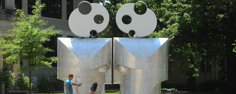 Students inspect the sculpture "Eye to Eye" by Barry Gunderson in front of Kent Hall.