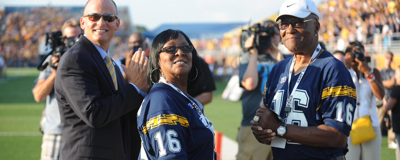 The parents of Kent State alum and NFL player James Harrison, Mildred and James Sr., along with Kent State Director of Athletics Joel Nielsen, watch as their son's jersey is retired.