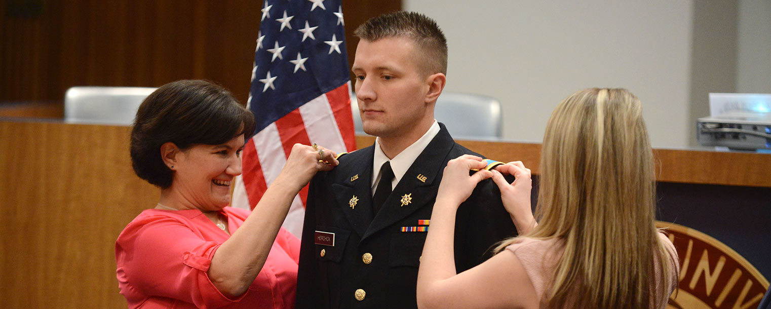 Newly commissioned U.S. Army 2nd Lt. David Herchick gets his bars pinned on by his mother on one side and his wife on the other during a commissioning ceremony.