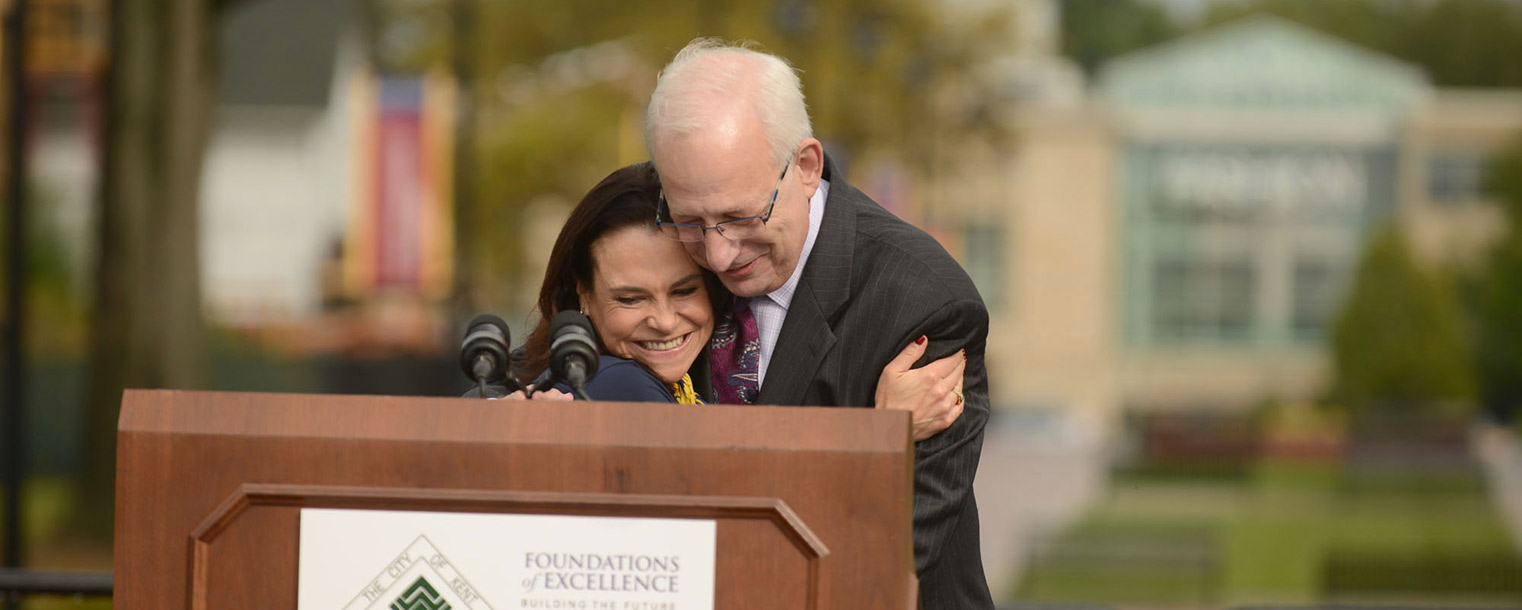 Jane Murphy Timken, chair of the Kent State University Board of Trustees, hugs Kent State President Lefton after announcing that the Kent State University Esplanade will be named the Lester A. Lefton Esplanade honoring him.