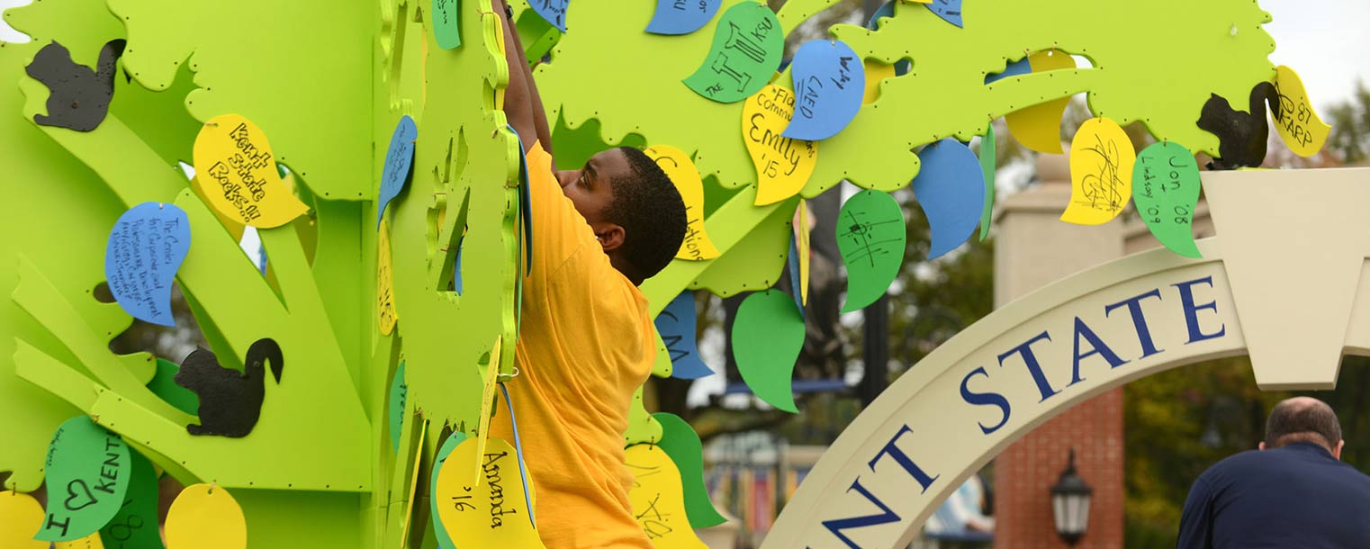 A Kent State student attaches handcrafted leaves to the Partnership Tree float.