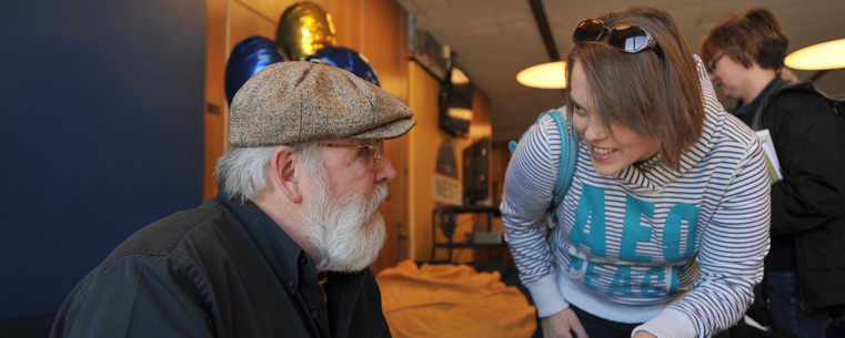 <p>Comic strip artist Chuck Ayers shares a laugh with a student during a book signing at the grand opening of The Nest in the Kent Student Center.</p>
