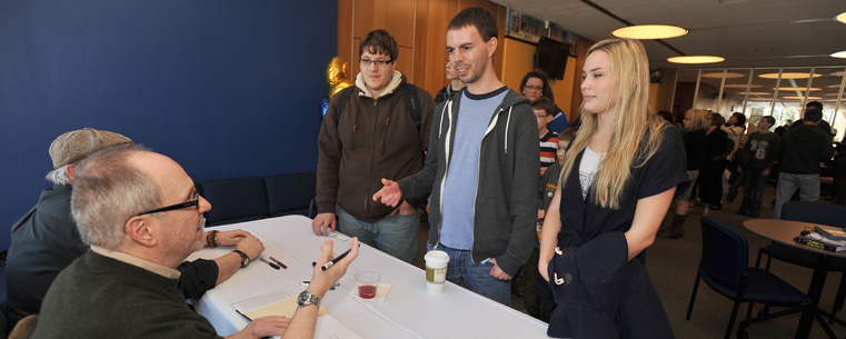<p>Tom Batiuk and Chuck Ayers sign autographs for students during the grand opening of The Nest.</p>
