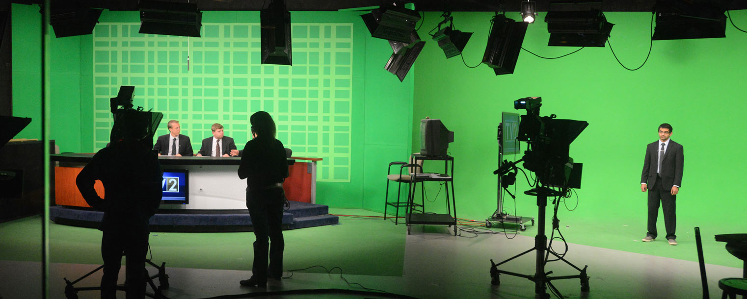 Shown is the view of the TV2 studio from the control room. The green screens are filled in with photos or weather maps.