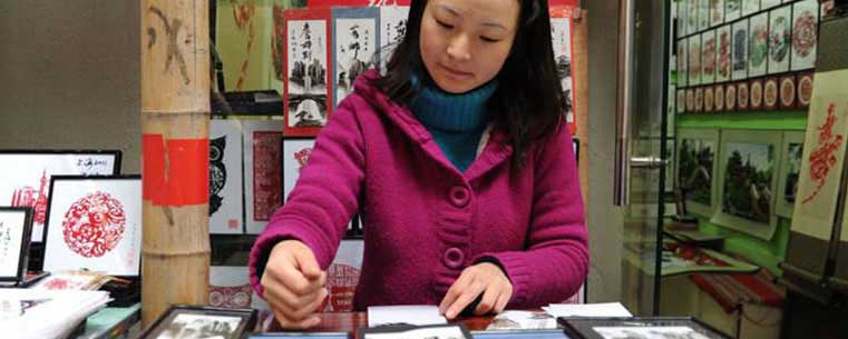 Helen Yan uses her skill of finger painting, which she learned from her uncle eight years ago, as her primary source of income. She owns a shop in the Tianzefang shopping district of Shanghai. Photo by Emily Horne.