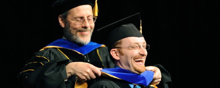 A doctoral degree recipient, right, reacts while being hooded during the advanced degree ceremony in the Memorial Athletic and Convocation Center. <br />
<br />