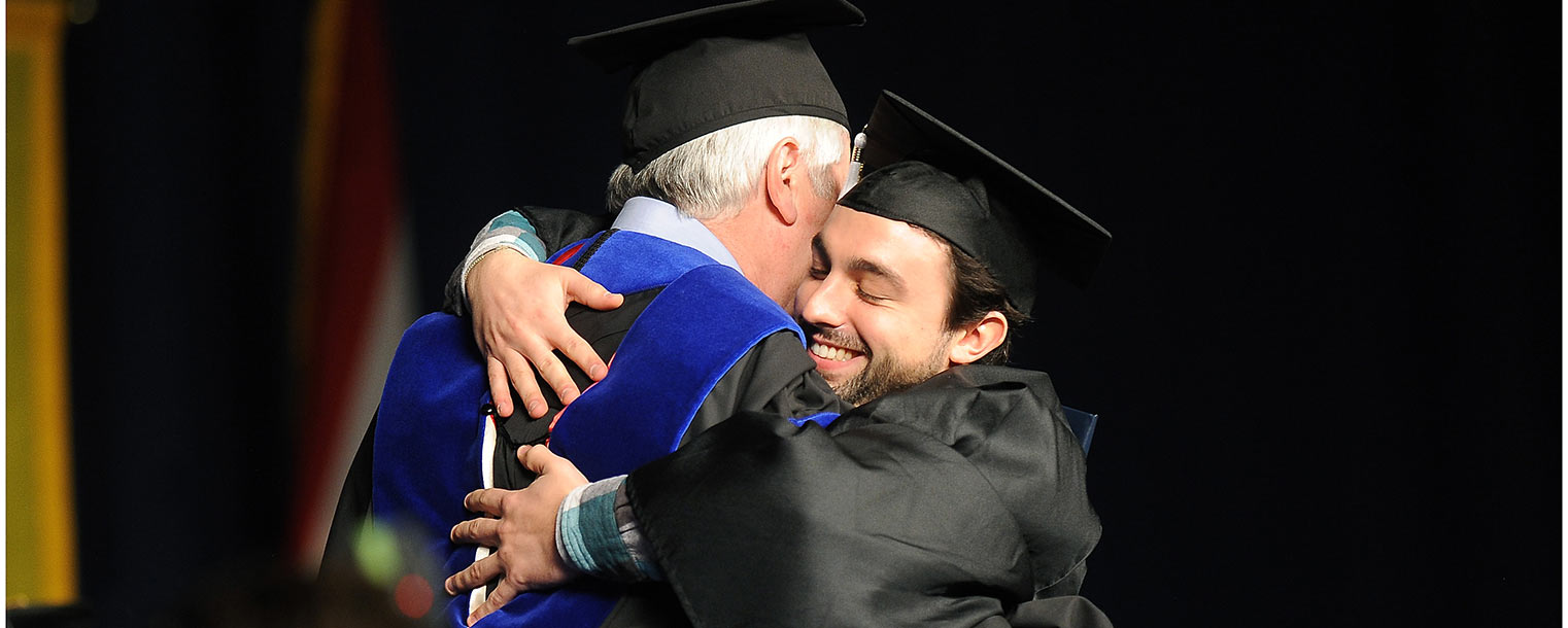 A Kent State student shares a hug with his dean after receiving a degree during the fall Commencement ceremony.