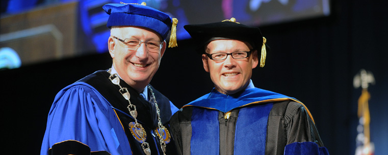 President Lefton presents morning commencement speaker Dr. Gregory P. Crawford with an alumni award.