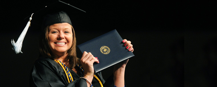 <p>An undergraduate student displays her diploma, and a proud grin, following commencement ceremonies.</p>