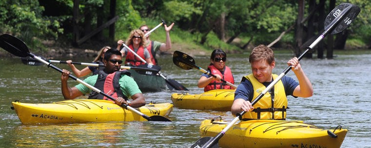 Kent State students make their way down the Cuyahoga River near downtown Kent in kayaks.