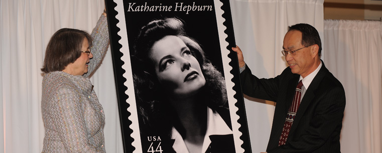 <p>Jean Druesedow, director of the Kent State University Museum, helps W. Spencer Hsu, the postmaster of Cleveland unveil a stamp honoring the late Actress Katharine Hepburn during a "Lunch With Kate" event held at Sammy's at Legacy Village.</p>