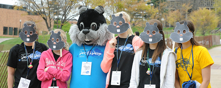 Kent State students and their siblings pose with cutout masks during Lil’ Sibs Weekend last year.