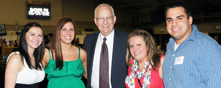 President Lefton poses for a photo with two 2012 graduates and their parents at the Flashes Forever event.