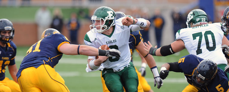 Kent State defensive players swarm around, and sack, the Eastern Michigan Eagle's quarterback at Dix Stadium.