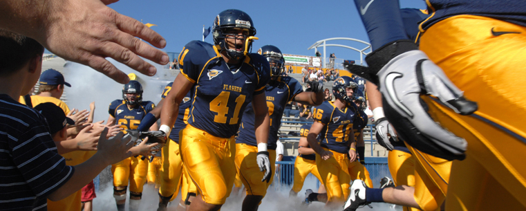 Kent State football players are welcomed onto the field by fans gathered in the end zone at Dix Stadium.