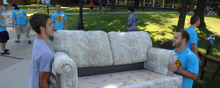 A student helps an incoming freshman move a couch to the fourth floor of Manchester Hall.