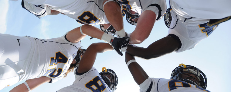 <p>Members of the Golden Flashes give each other encouragement just before the start of the game.</p>