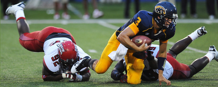 <p>Kent State's quarterback twists through a pair of Louisiana defenders.</p>