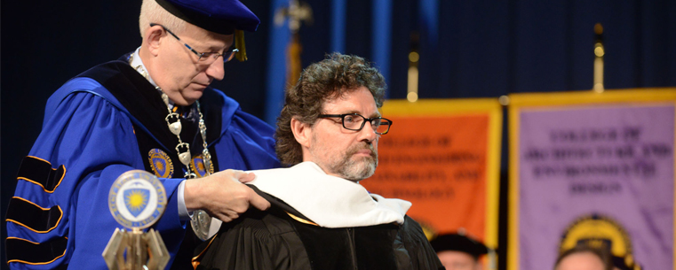 <p>Kent State President Lester A. Lefton hoods Kent State alumnus Jeff Richmond during the morning commencement ceremony, giving Richmond an honorary Ph.D. Richmond is an alumnus of Kent State's School of Theatre and Dance.</p>