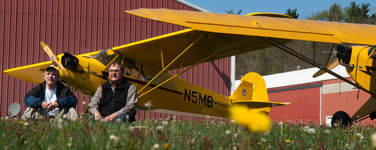 Pilots Joe Murray and Ron Siwik are pictured at the Portage County Airport with the two 1946 Piper J3 Cub aircraft they will fly to Dayton-Wright Brothers Airport. The two aviators plan to make consecutive landings in all of Ohio’s 88 counties. They will spend more than 26 hours aloft on the 1,670 nautical mile flight to honor the 75th anniversary of the Piper Cub. (Photo courtesy of Gary Harwood)