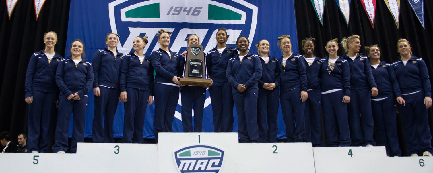 The Kent State women’s gymnastics team stands on the podium with its trophy for winning the regular season MAC title.