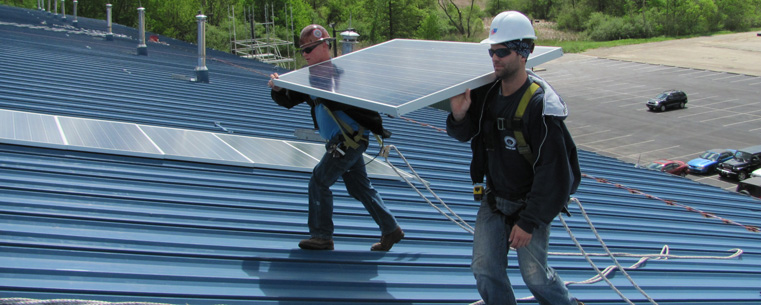 Workers install solar panels on the Kent State University Field House. The project, scheduled to be completed in early July, is the first renewable energy project for Kent State.