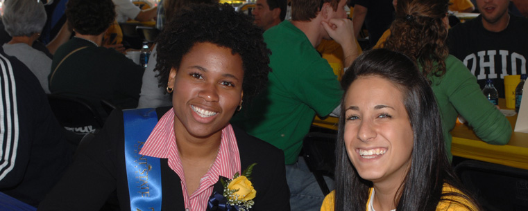 <p>Two students play cards at a fan event before a football game.</p>