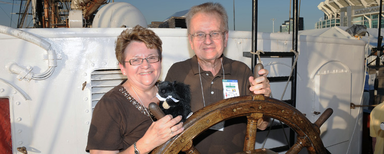 <p>Guests at the President Lefton's Cleveland Tall Ships Festival reception pose behind the wheel of the Roald Amundsen, a tall ship from Germany.</p>