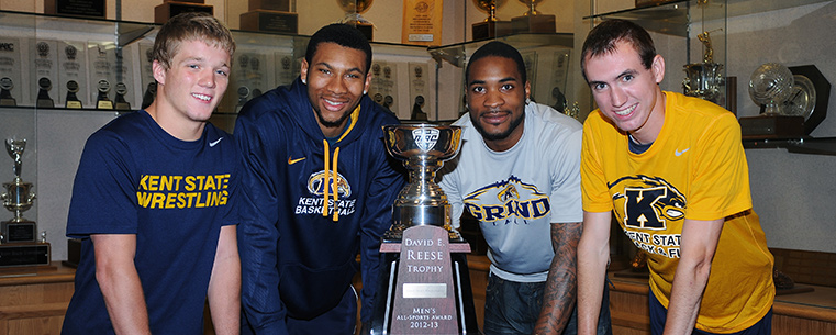 Kent State student-athletes gather around the 2012-13 Reese Trophy in the Memorial Athletic and Convocation Center. Pictured are wrestler Mack McGuire, basketball player Devareaux Manley, football wide receiver Tyshon Goode and cross country runner Samuel Allen.