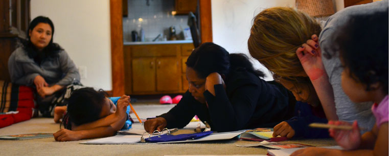 Kent State University students volunteer their time home-tutoring, helping refugees transition to day-to-day life in America. The group gathers on the floor and begins to study. (Photo courtesy of Jacob Byk, Daily Kent Stater)