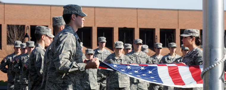 <p>Members of the Kent State ROTC detachment stand at attention during the raising of the United States flag, over Risman Plaza.</p>