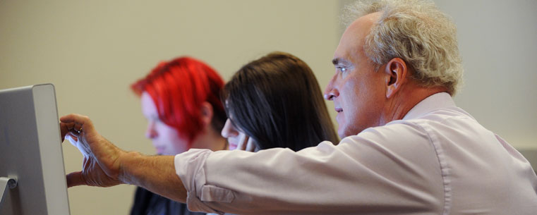 Kent State students receive instruction from a professor in a web sciences classroom in Franklin Hall.