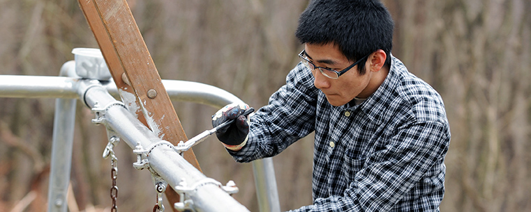 A Kent State student volunteer works on repairing playground equipment in East Liverpool during a Kent State alternative spring break trip.