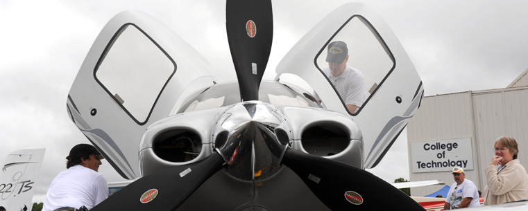 <p>Visitors at a previous Aviation Heritage Fair look over an airplane parked at the Kent State University Airport.</p>