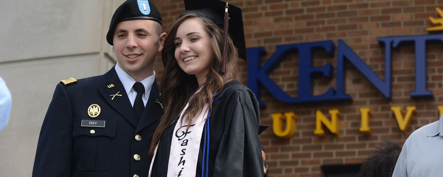 An Army ROTC graduate poses with his friend who graduated from the Fashion School during Kent State's summer 2013 commencement.