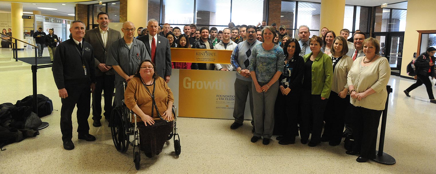 Faculty, staff and students from Kent State’s College of Applied Engineering, Sustainability and Technology pose for a picture in the Kent Student Center with an I-beam that will be installed in the college’s new building. The I-beam was then signed by students and employees.