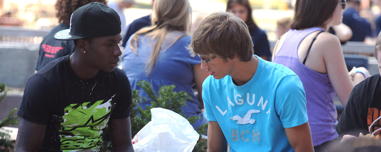 <p>Two incoming freshman look over orientation materials while eating lunch in the Risman Plaza.</p>