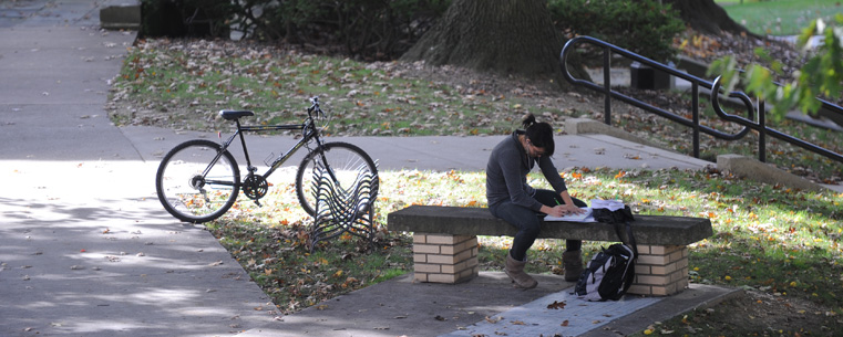 <p>A student studies near McGilvery Hall.</p>