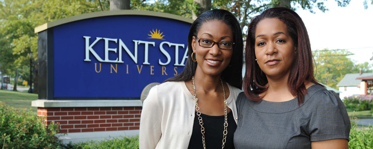 Gina Stikes-Shoehalter and her sister, Joan Stikes-Jenkins pose in front of the Kent State sign near Franklin Hall.